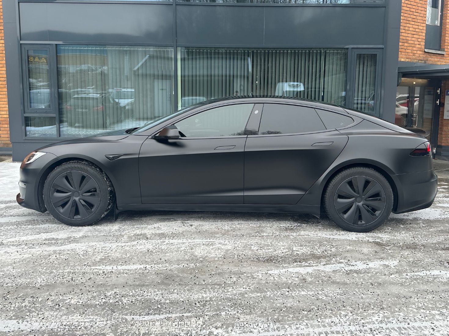 Matt-foliert Tesla på snødekket bakke om vinteren